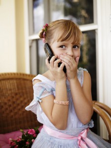 Girl (6-7) using mobile phone, covering mouth with hand